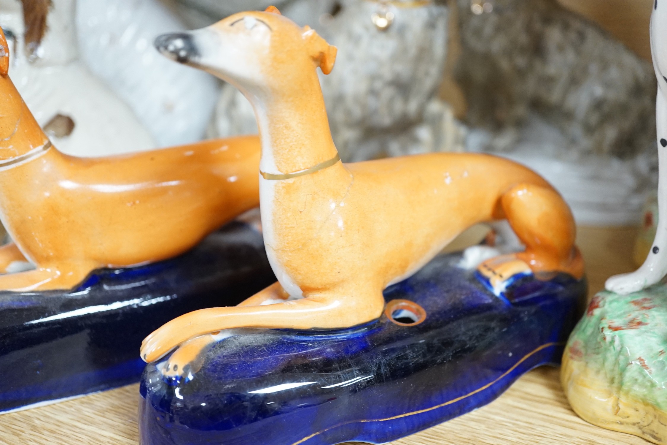 A mixed collection of mostly Staffordshire pottery models of recumbent dogs, hounds, etc. to include Dalmatians- 19.5cms high